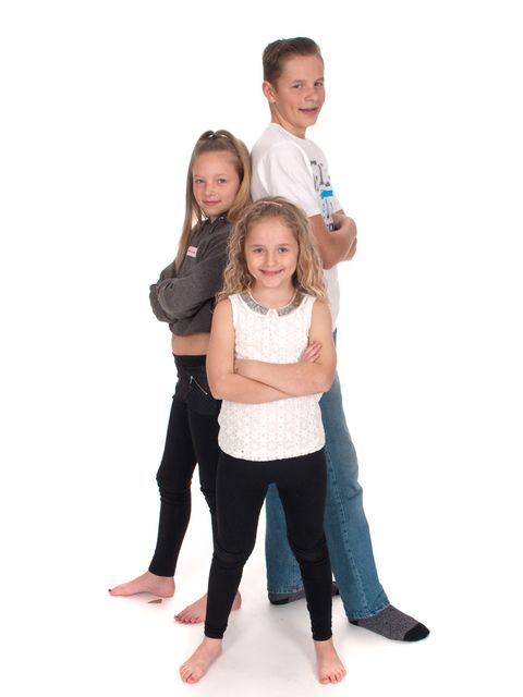 three children standing with arms folded on a white background