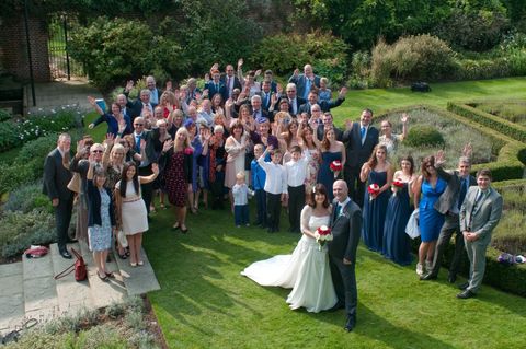 wedding guest group picture outside bride and groom standing in front of all the guests looking up to the photographer above