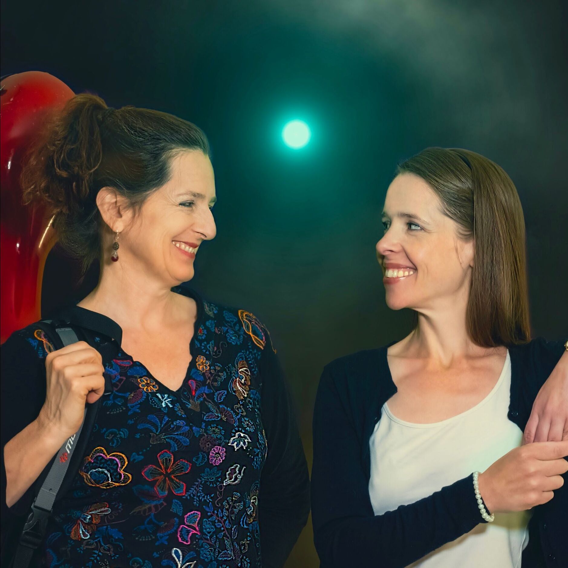Zwei Cellistinnen mit Cellokoffern – Leana Luzius und Sue Schlotte im Duo, fotografiert vor dunklem Hintergrund.