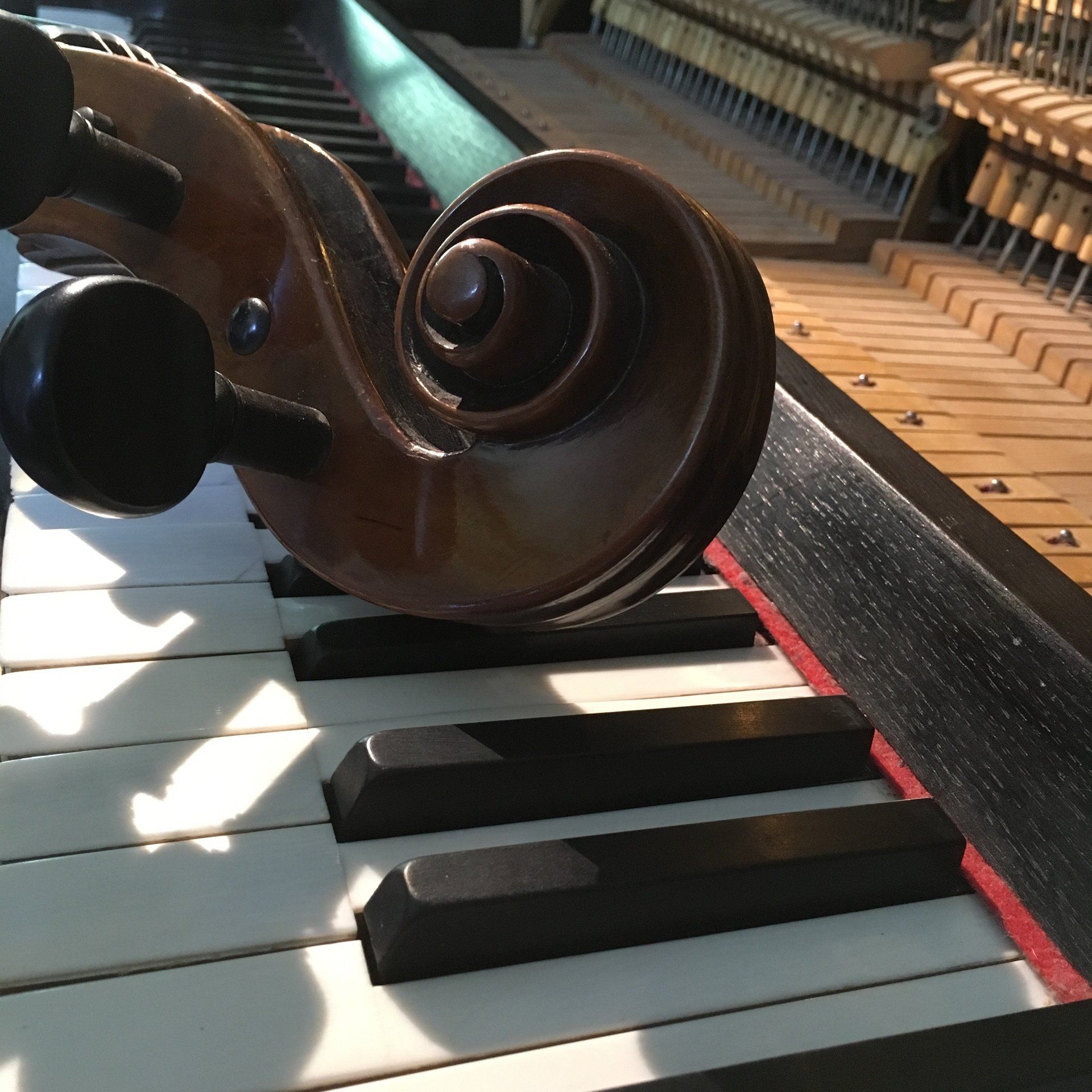 „Nahaufnahme des Cello-Halses und der Schnecke, liegend auf Klaviertasten – Artwork zur Kollaboration Goodheart & Schlotte, Album Departures.“