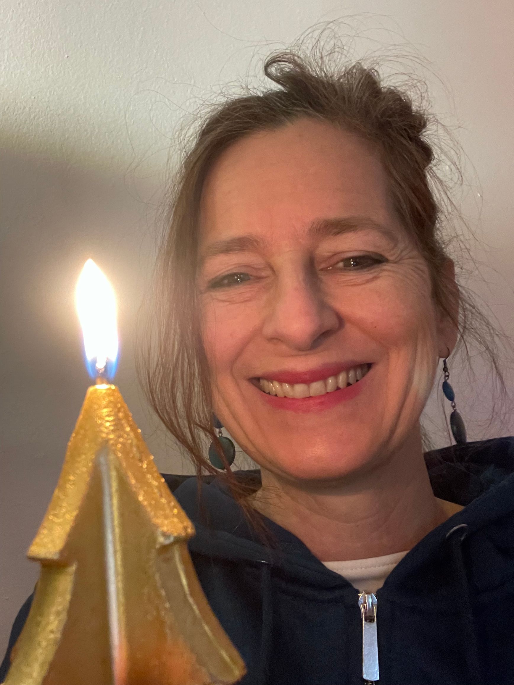 Foto von Cellistin Sue Schlotte mit einer weihnachtlichen Kerze.