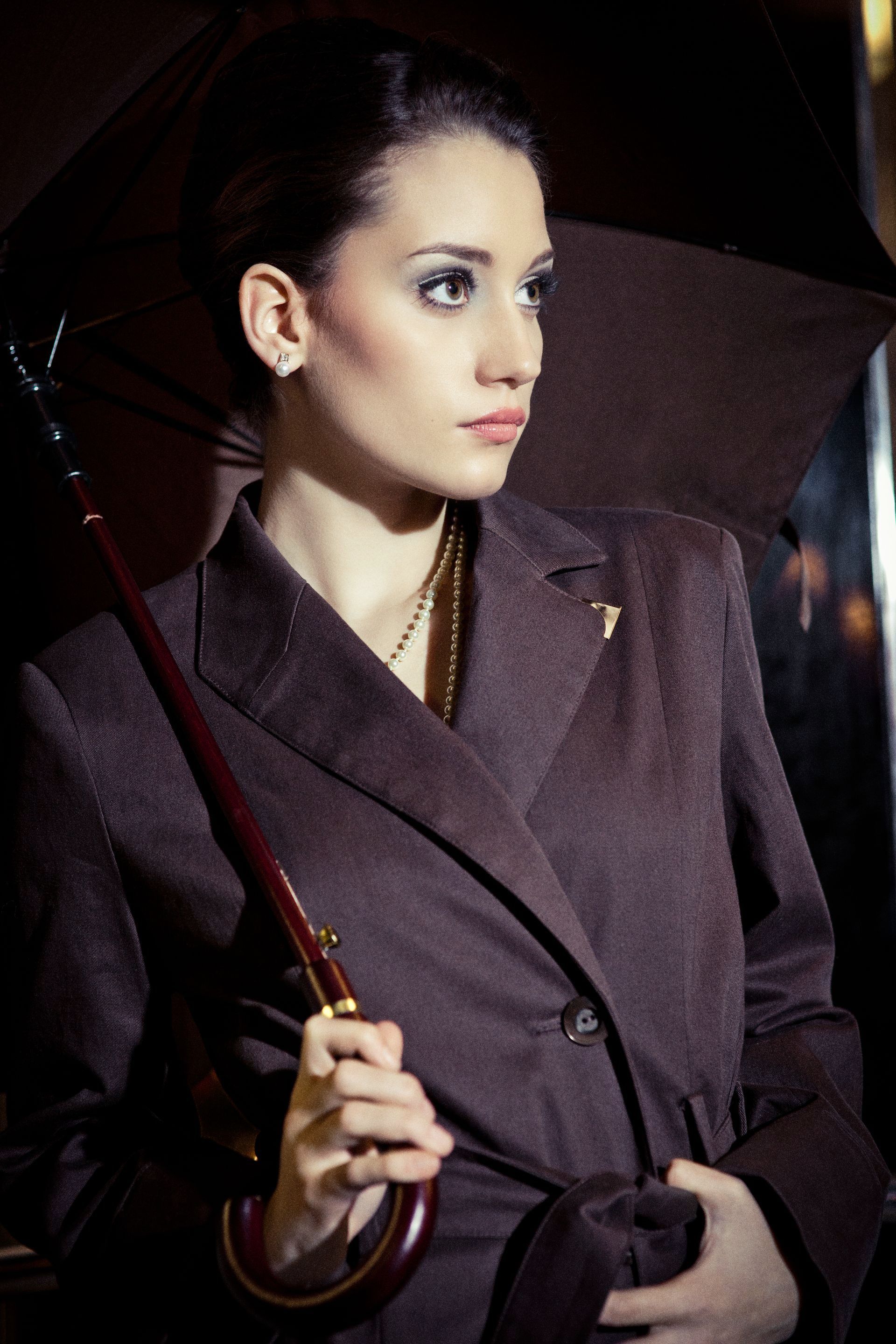 Frau mit schwarzem Trenchcoat und schwarzem Regenschirm.