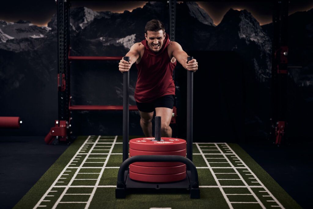 Mann beim Schieben schwerer Gewichte – Functional Training im modernen Trainingsbereich von New Mountains