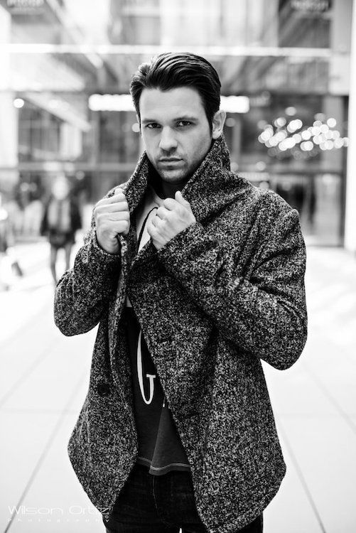 Schwarz Weiß Foto Mann steht und hält sich den Kragen seiner Jacke