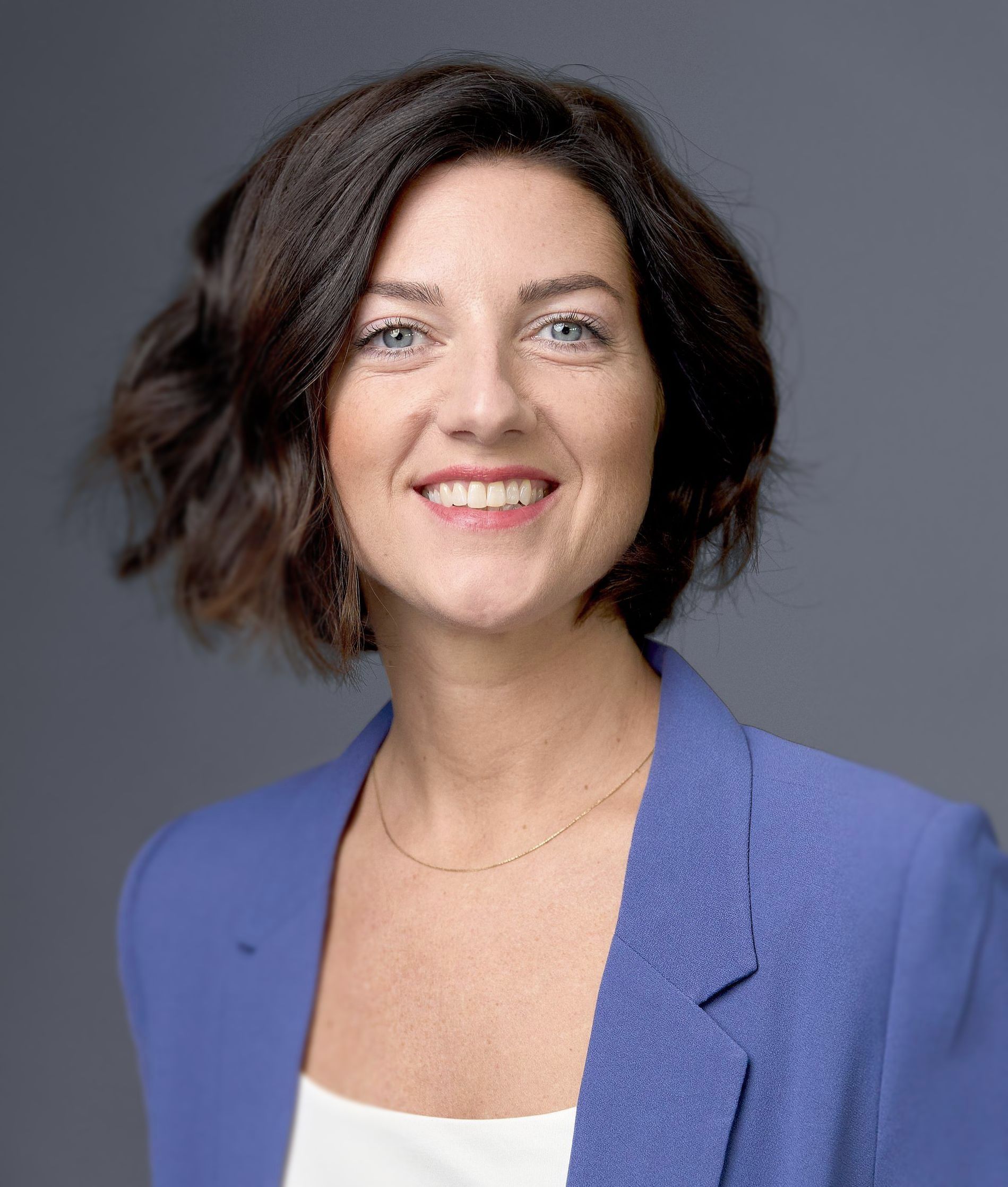 Portrait von Julia Ebert, Hair- & Make-up Artist. Sie trägt einen blauen Blazer und ein weißes top darunter.
