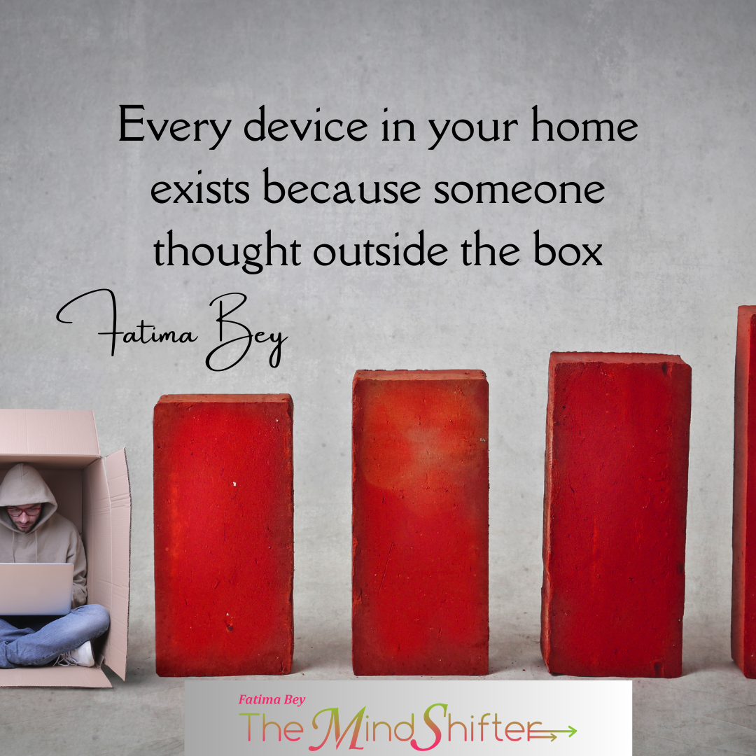 Person working in cardboard box beside red blocks with quote 'Every device in your home exists because someone thought outside the box' by Fatima Bey.