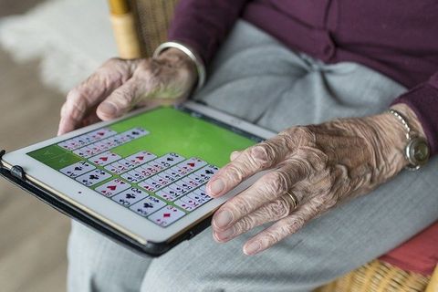 personne âgée jouant sur tablette