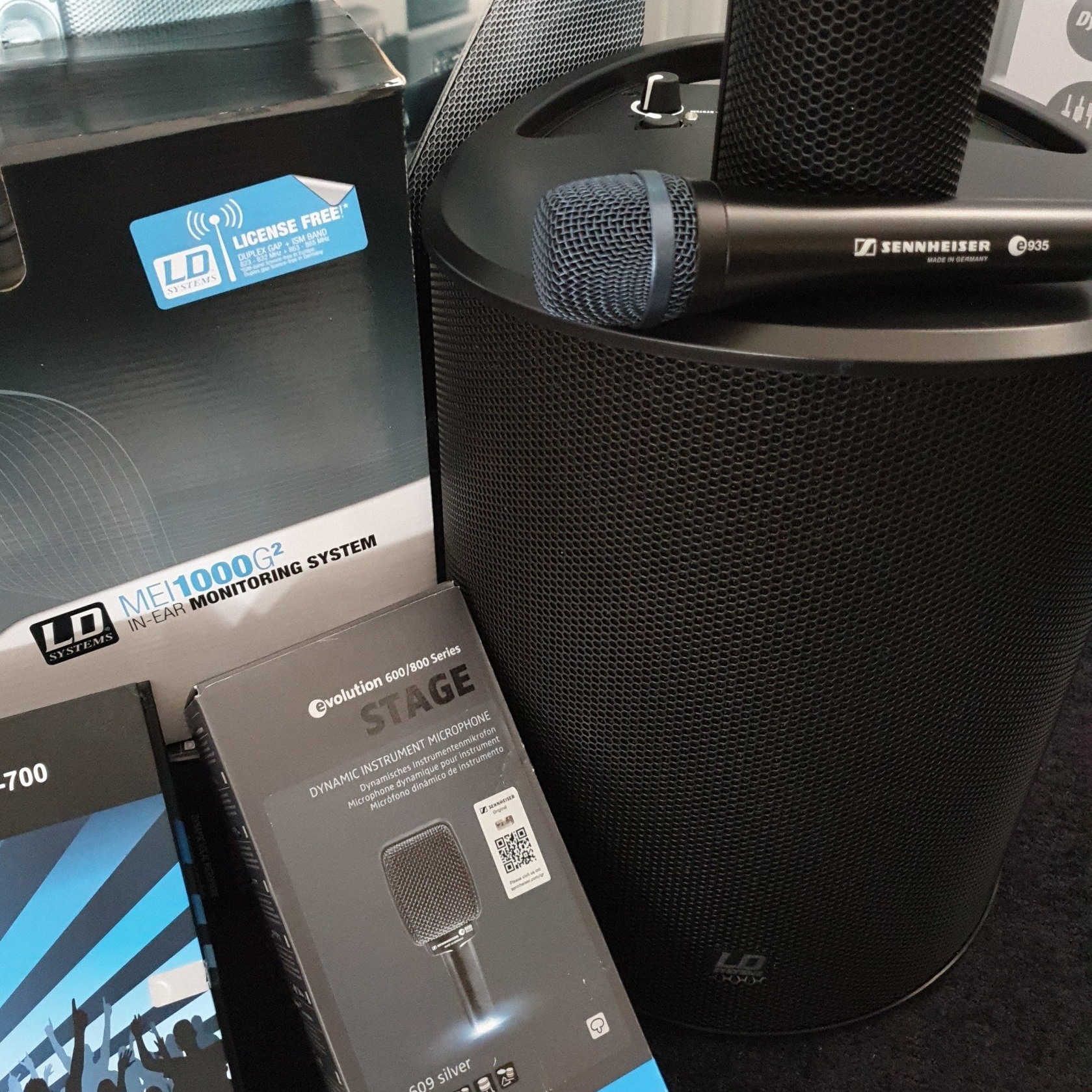 PA-Anlagen, Monitorboxen & Mikrofone u.v.m. Eine PA-Anlage auf der ein Mikrofon liegt und an der ein In-Ear-System lehnt.