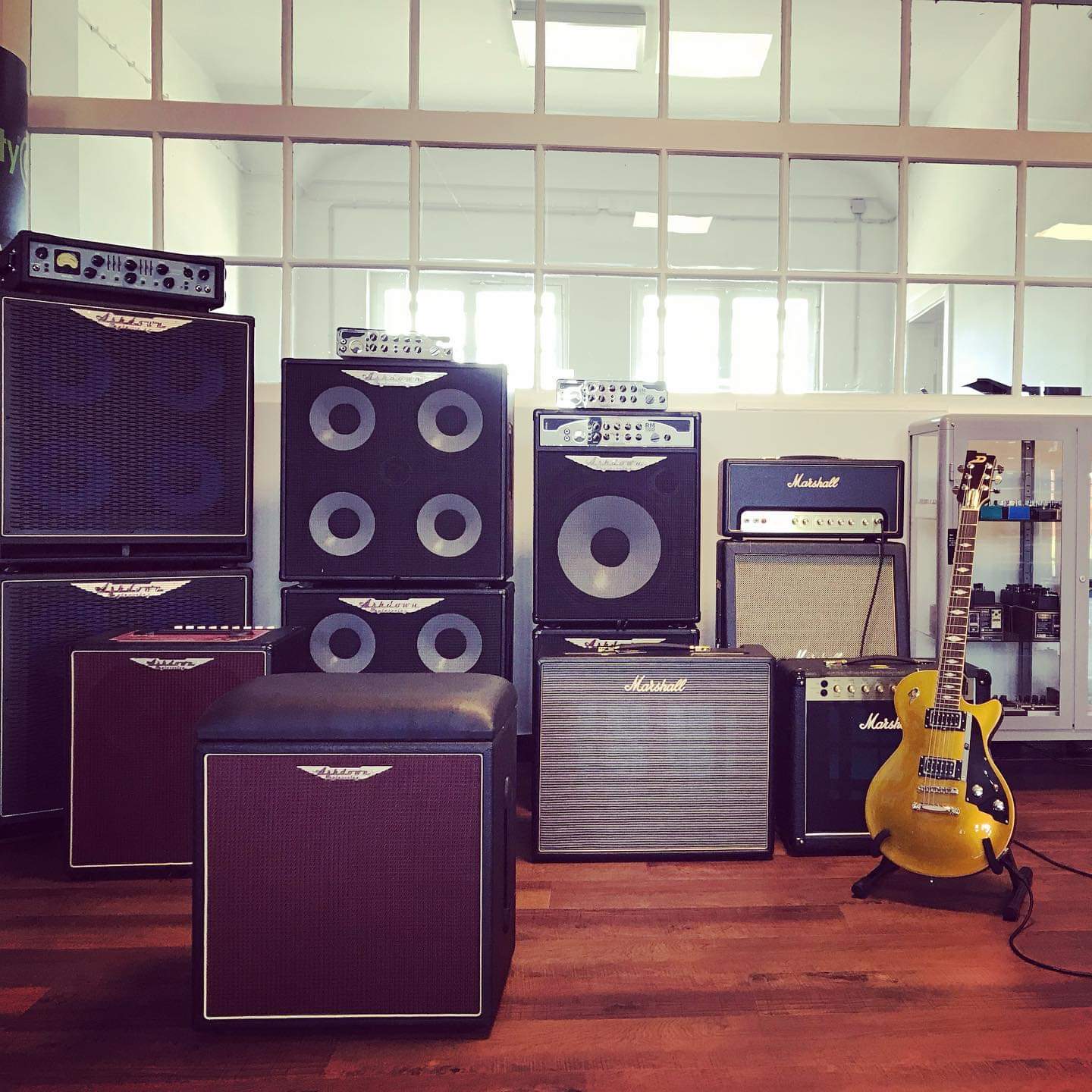 Wampler, Diezel, Friedman, Ashdown, Marshall, Vox Eine Wand von Verstärkern, Boxen und eine Vitrine mit Effektgeräten.