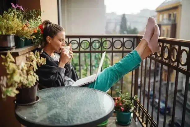 Eine junge Frau sitzt auf dem Balkon und hat mit dem Mietkautionsvergleich Geld gespart.
