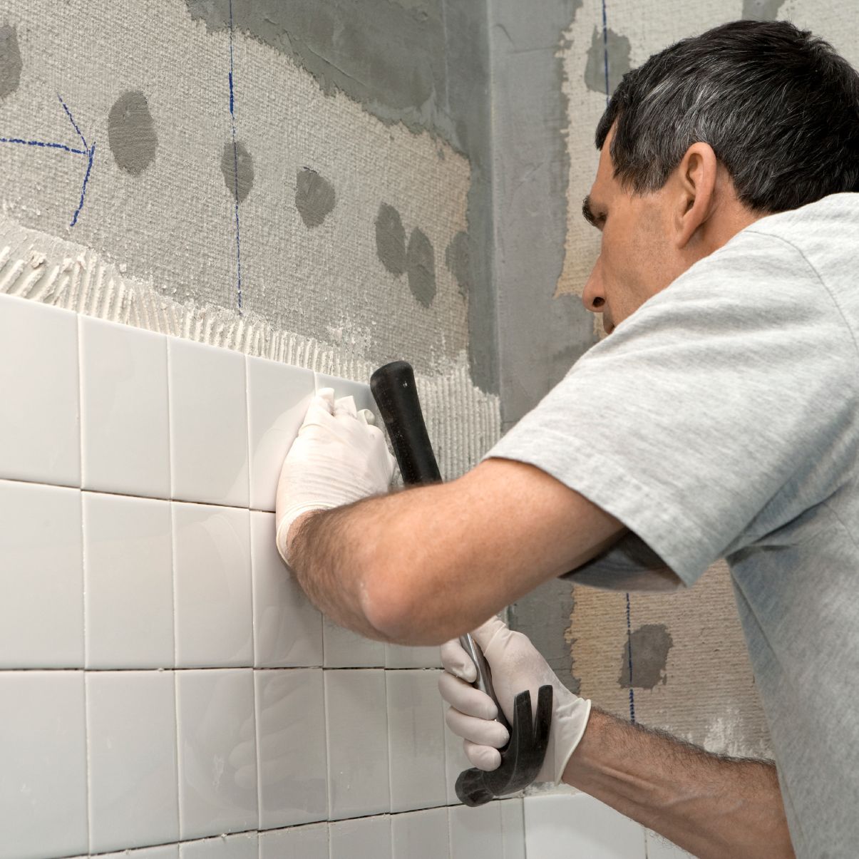 contractor installs white tile with grout in bathroom renovation