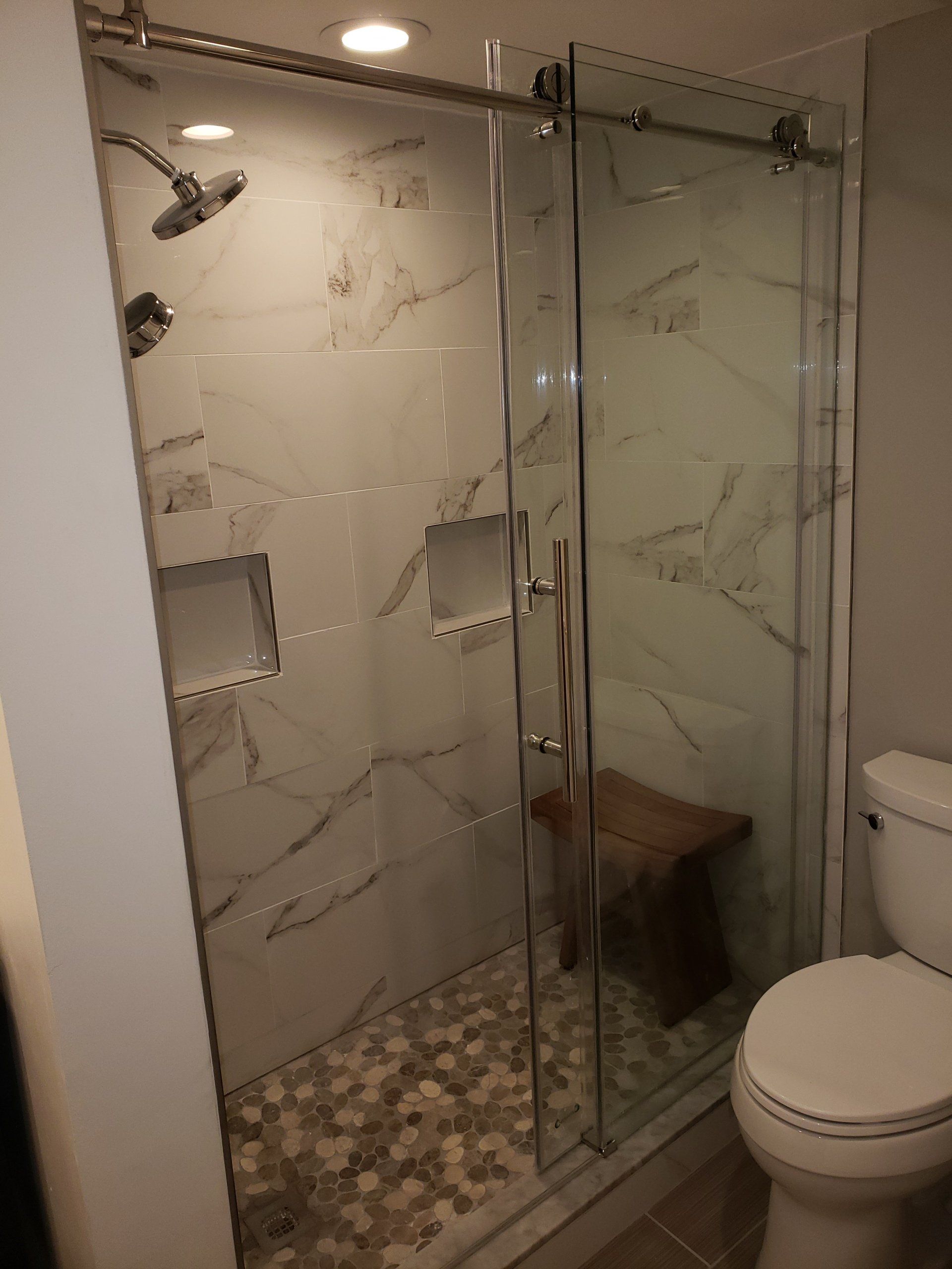 glass shower sliding doors, tile interior and two shower niches