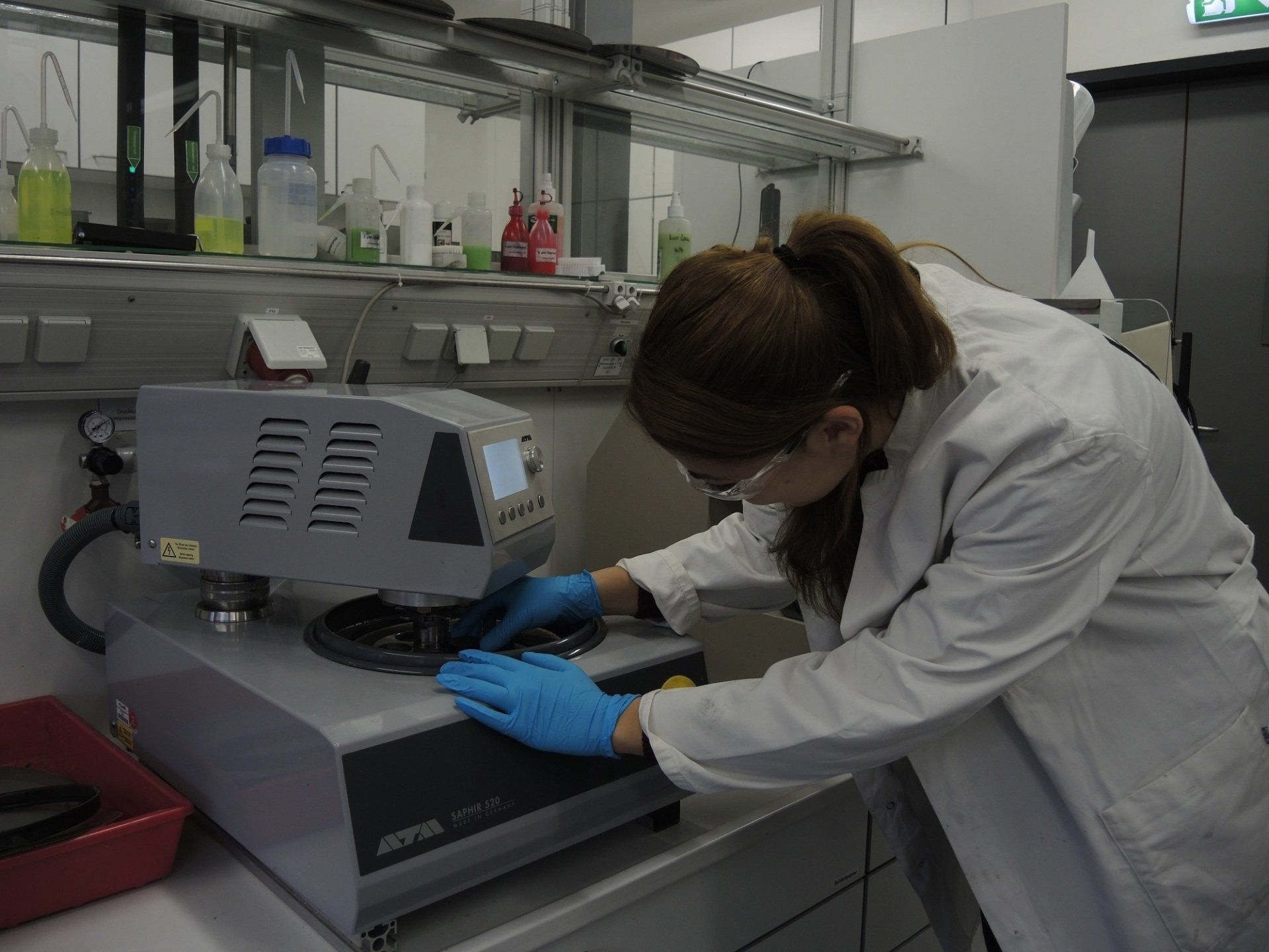 Das Foto zeigt eine Mitarbeiterin beim Einlegen einer Probe in ein Mikroskop.