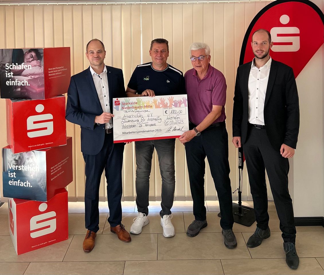 Spende in Höhe von 1.000 Euro an Tennisfreunde Aiterhofen e.V. Die Sparkasse Niederbayern-Mitte ist für die Gesellschaft aktiv und setzt sich für Vereine und Institutionen vor Ort ein. Daher gab es auch im Jahr 2023 wieder eine besondere Spendenaktion: Mitarbeiterinnen und Mitarbeiter der Sparkasse konnten selbst Vereine für eine Spende vorschlagen oder die Vereine haben sich die Mitarbeiter als „Spendenpaten“ ausgesucht. Unter den glücklichen Spendenempfängern waren auch die Tennisfreunde Aiterhofen. Christian Weinzierl, Leiter der Geschäftsstelle Straßkirchen - Aiterhofen, übergab gemeinsam mit Finanzberater Maximilian Seidl einen symbolischen Spendenscheck an den Vorstand Christian Preiss und Kassier Peter Sieber. „Die Sparkasse Niederbayern-Mitte setzt sich für die regionalen Vereine und Institutionen ein“, betonte der Geschäftsstellenleiter. „Ich freue mich sehr, dass durch unsere Spenden viele Projekte und Anschaffungen erst möglich gemacht werden.“ „Die Tennisfreunde Aiterhofen haben von dieser finanziellen Zuwendung einen Motorbesen für den Tennisplatz angeschafft.“ Sie bedankten sich herzlich bei der Sparkasse Niederbayern-Mitte für die finanzielle Unterstützung. Bildunterschrift (v.l.n.r.): Christian Weinzierl (Leiter der Geschäftsstelle Straßkirchen - Aiterhofen), Christian Preiss (1. Vorstand), Peter Sieber (Kassier) und Maximilian Seidl (Finanzberater)