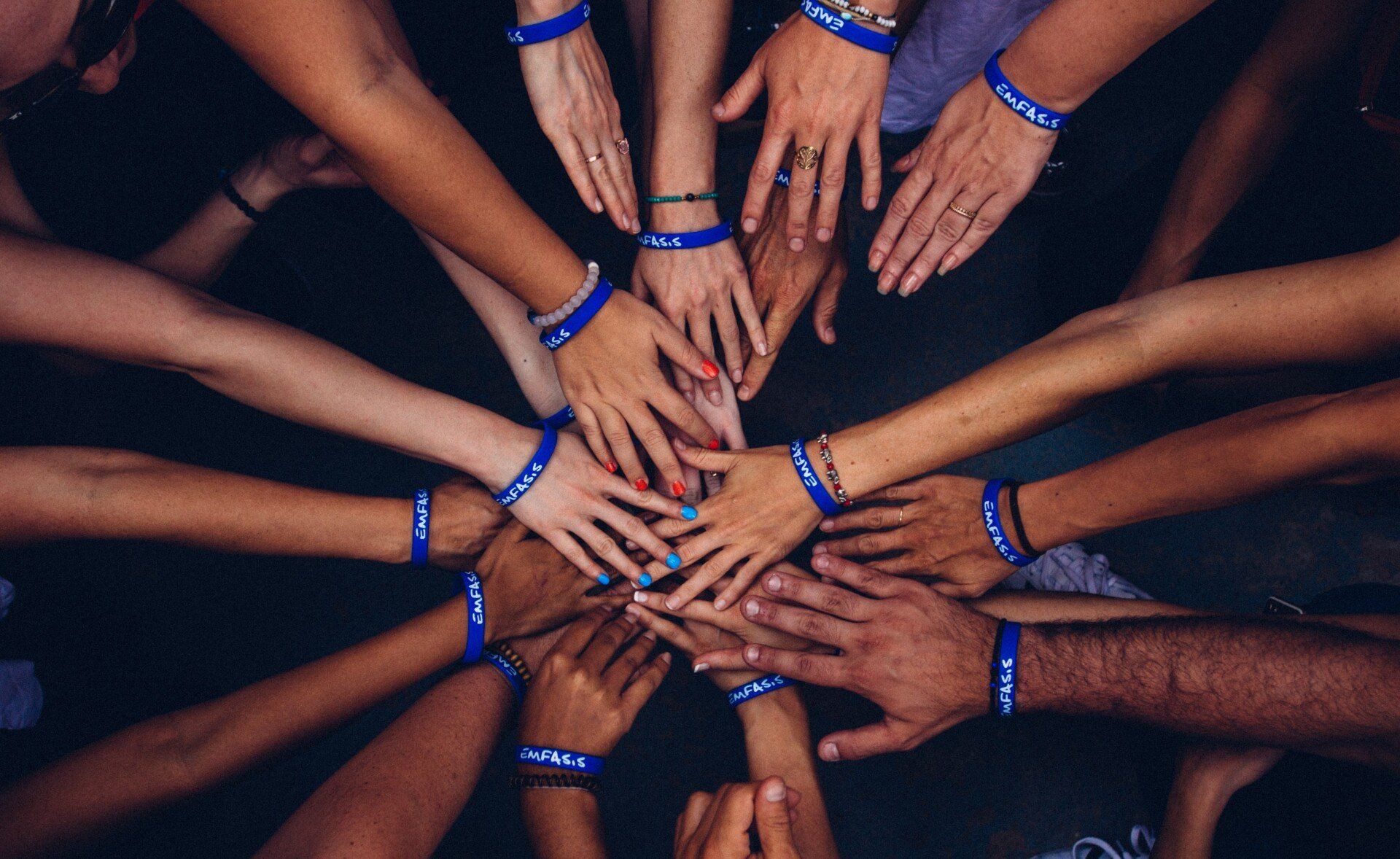 Blick von oben auf im Kreis aufeinandertreffende Hände