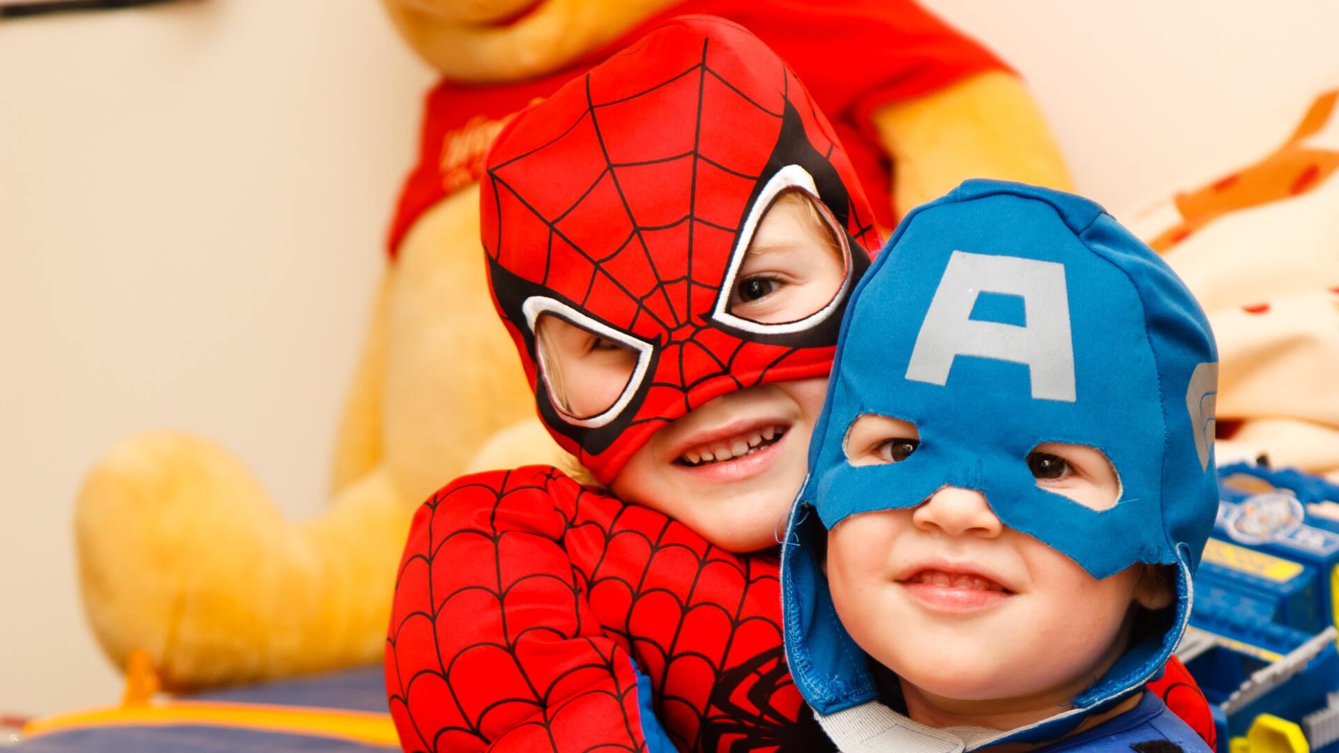 Zwei Jungen, verkleidet als Spiderman und Superman, lächeln in die Kamera
