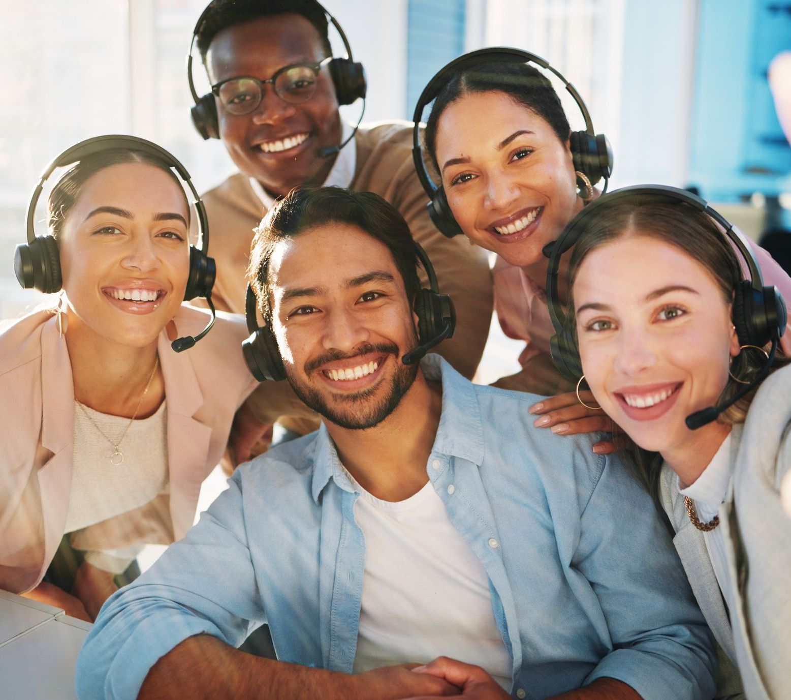 Mehrere Menschen verschiedenster Nationalitäten lachen und haben ein Headset auf.