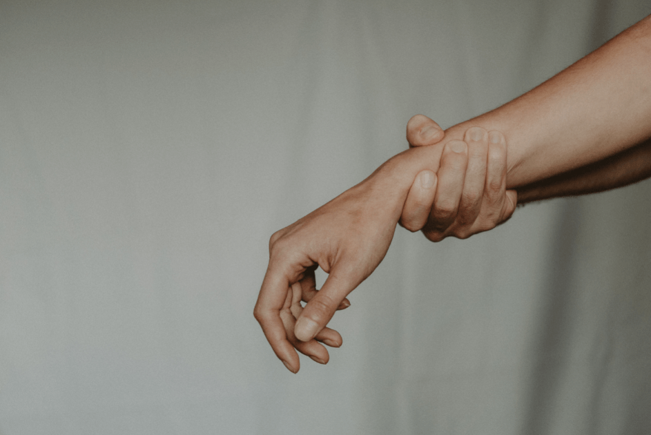 Mano de hombre agarrando por la muñeca el brazo de una mujer