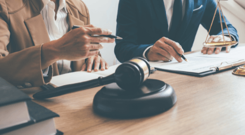 Mujer y hombre en juzgado escribiendo sobre una mesa