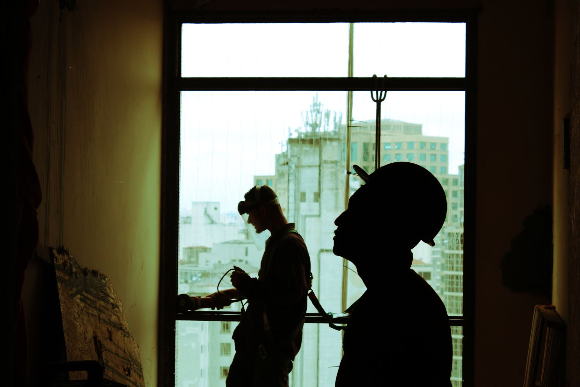 dos siluetas de trabajadores de la construcción con cascos en una obra