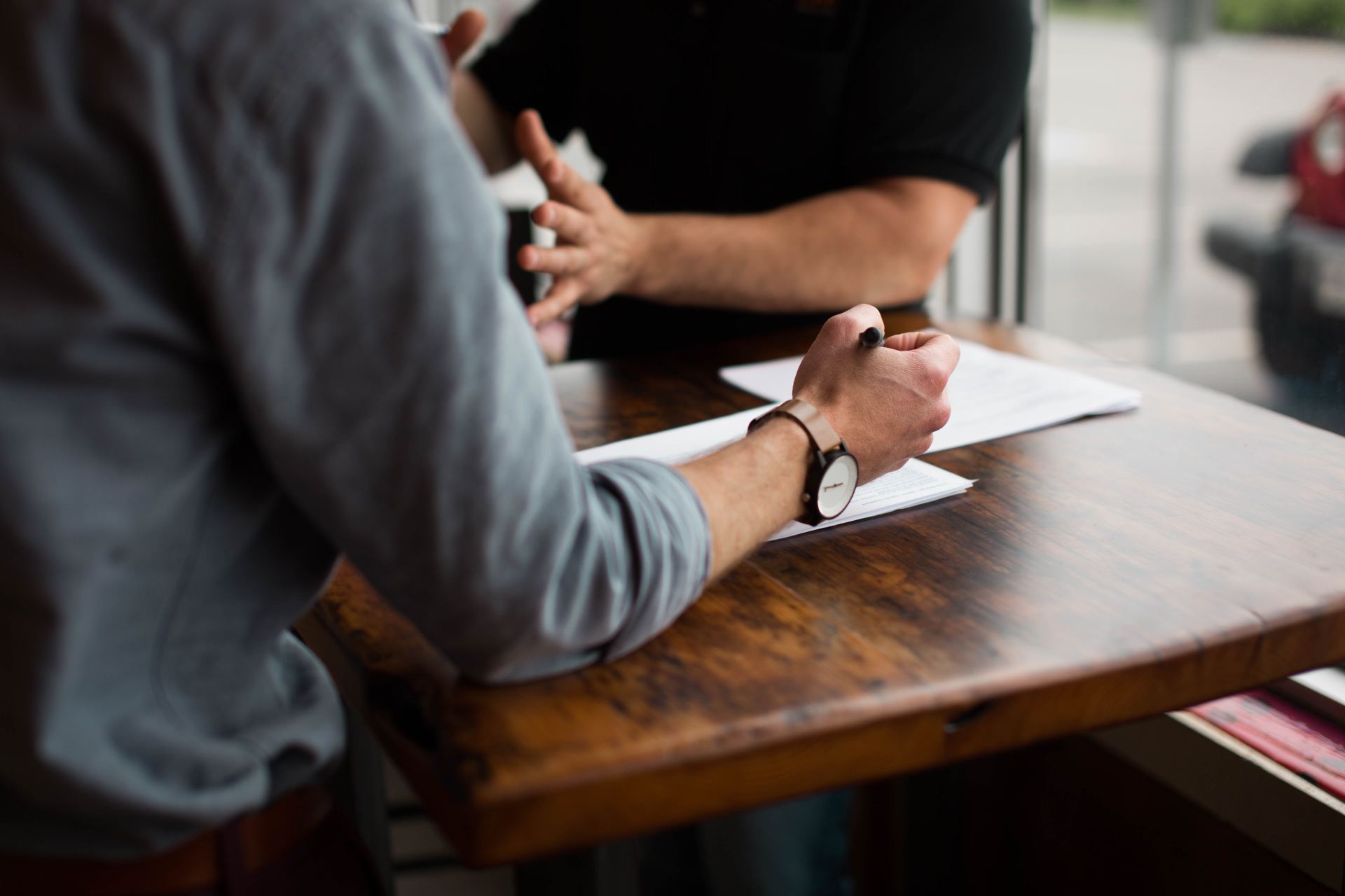 Dos personas hablando con sus manos sobre la mesa