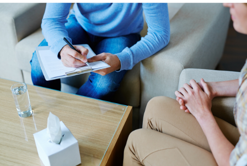 Persona en sesión de terapia con psicólogo tomando notas