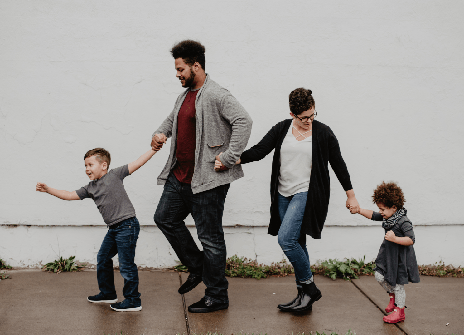 Capacidades parentales Niño, padre, madre y niña caminando de la mano por la calle sonriendo