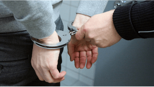 Imputabilidad Hombre con manos a su espalda siendo esposado por un policía
