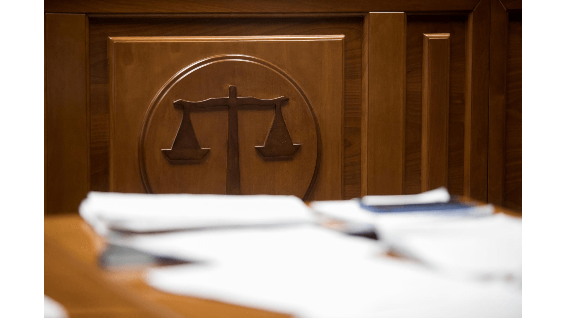 Sala de Juicio con símbolo de la justicia y documentos encima de una mesa