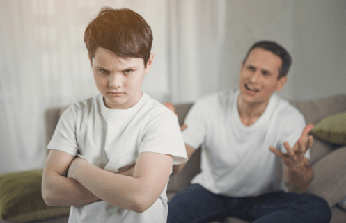 Problemas de conducta Niño enfadado de brazos cruzados mientras padre le grita desde el sofá