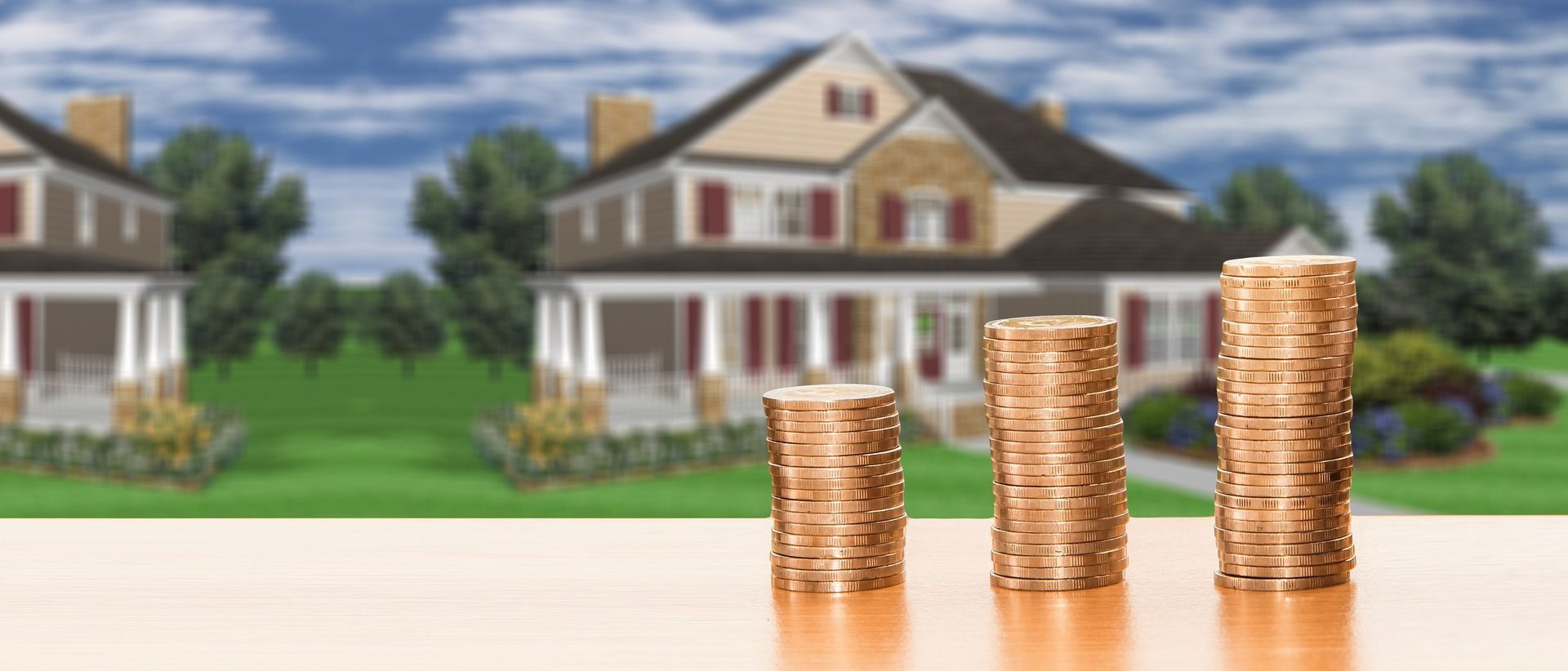 Haus und Münzstapel als Symbol für Budgetplanung und Finanzierung bei der Immobiliensuche