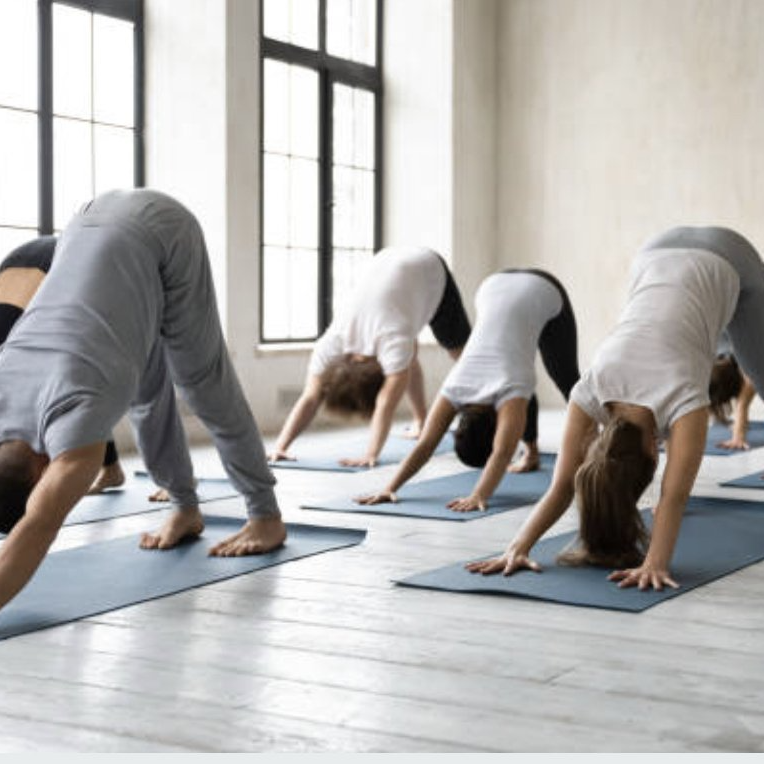 Manuela König (Yogalehererin) mit ihrer Schülerin Samira in einer Parnteryogapose auf einer Yogamatte vor einer Betonwand.