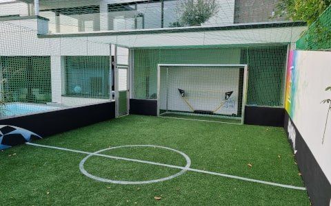 Soccercourt im Garten mit grünem Rasen blauem Pool