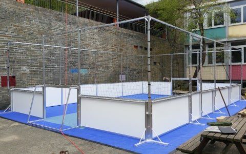 Soccercourt in weiß mit blauem Untergrund und Gebäuden im Hintergrund