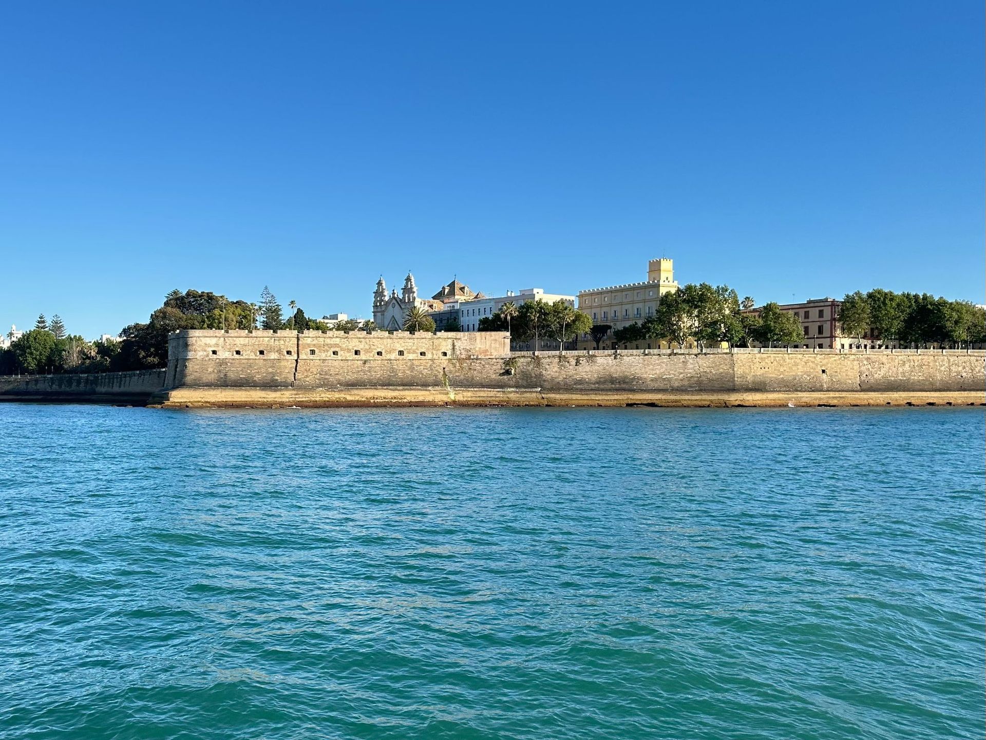 Vista panorámica del Baluarte de la Candelaria e Iglesia del Carmen de Cádiz desde el mar, con cielo