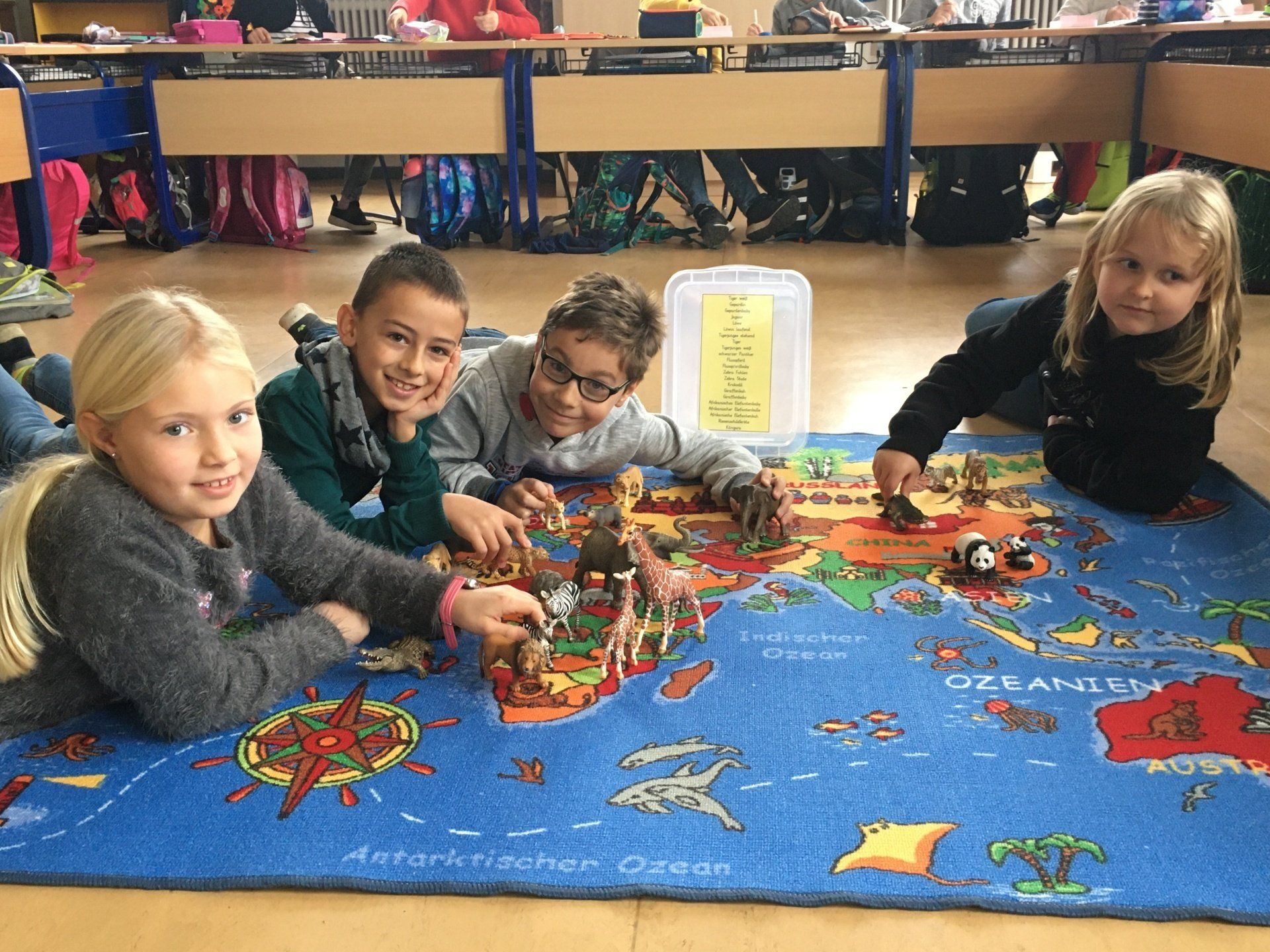 Kinder auf einem Lernteppich mit Spielfiguren