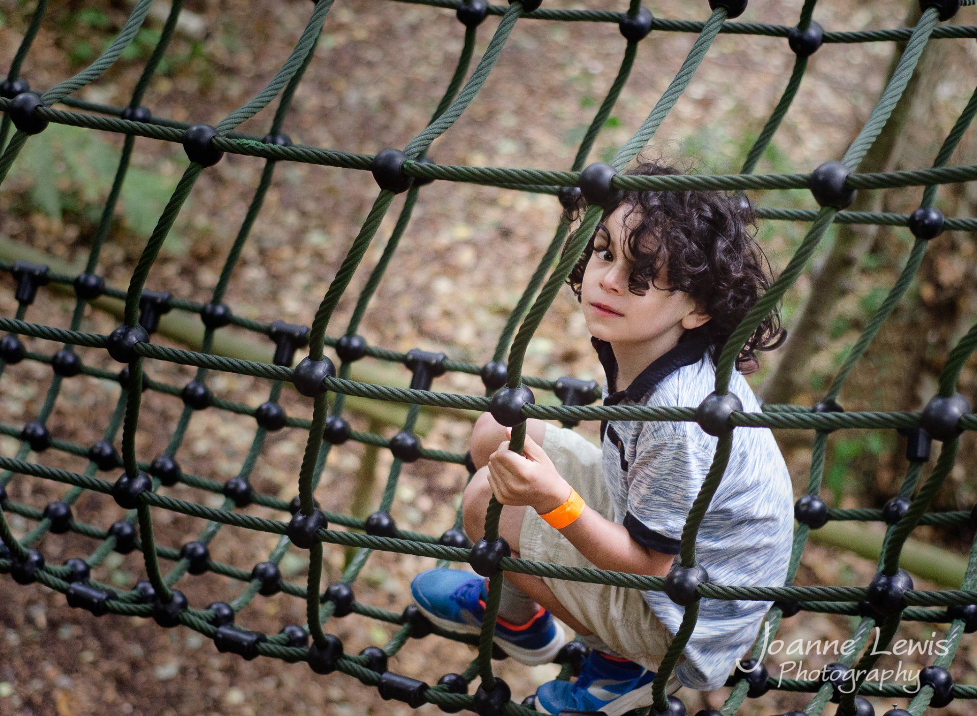 Boy climbing through rope net at Bewilderwood