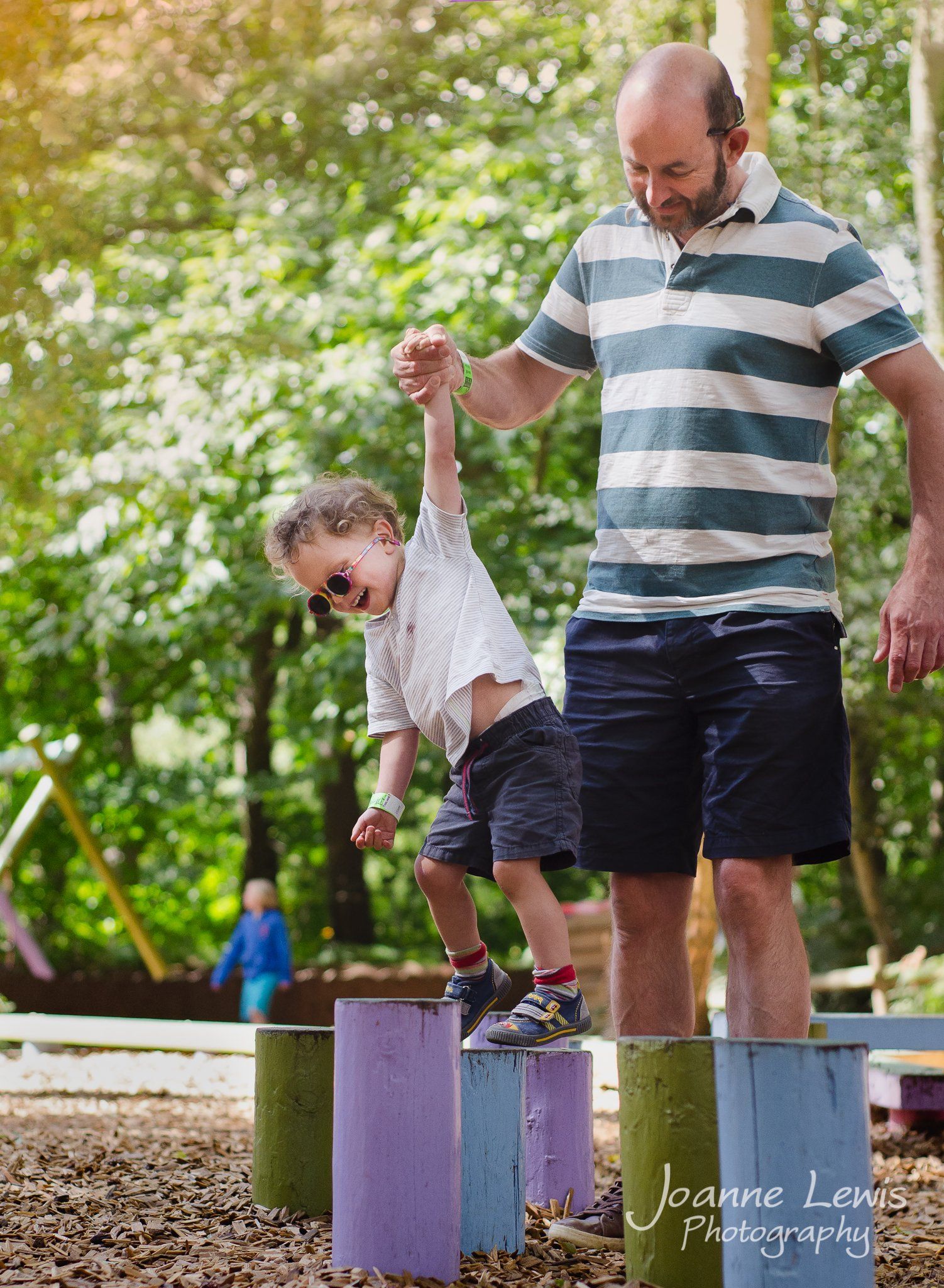 Boy climbing on stepping stumps at Bewilderwood with his dad