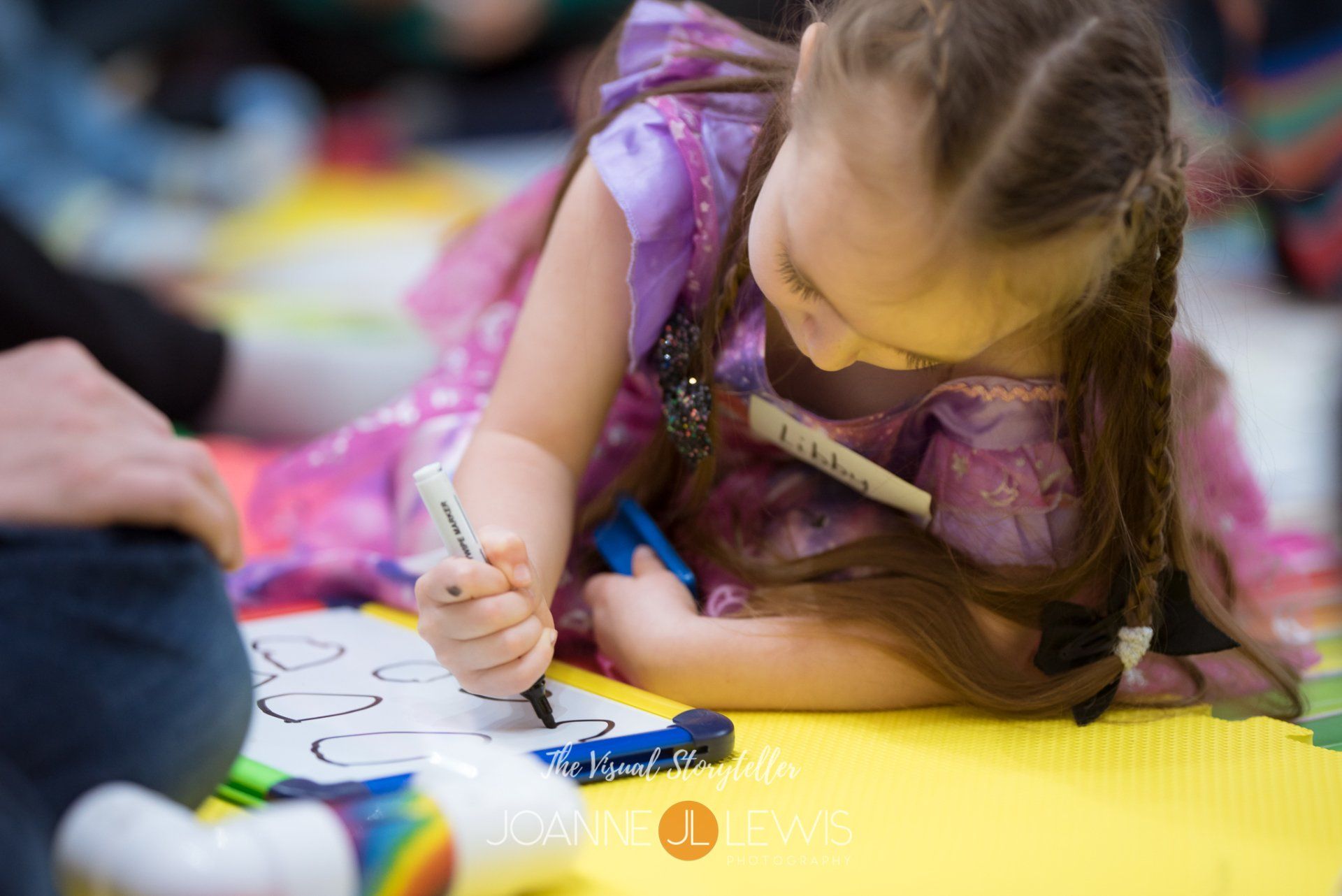 little girl in pretty lilac dress colouring on the floor