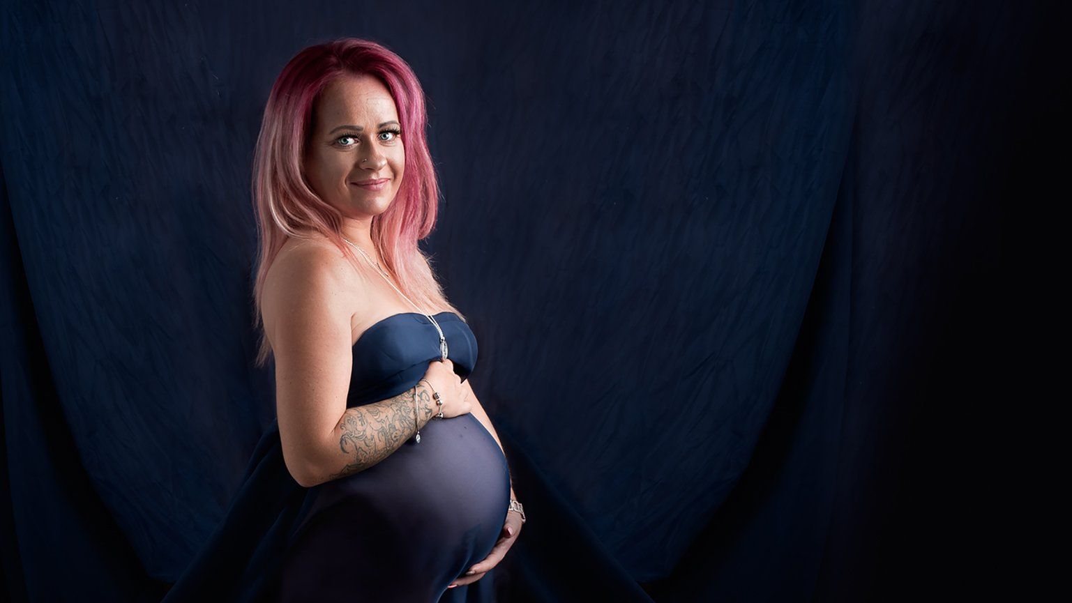 Nude maternity photoshoot wrapped in royal blue material
