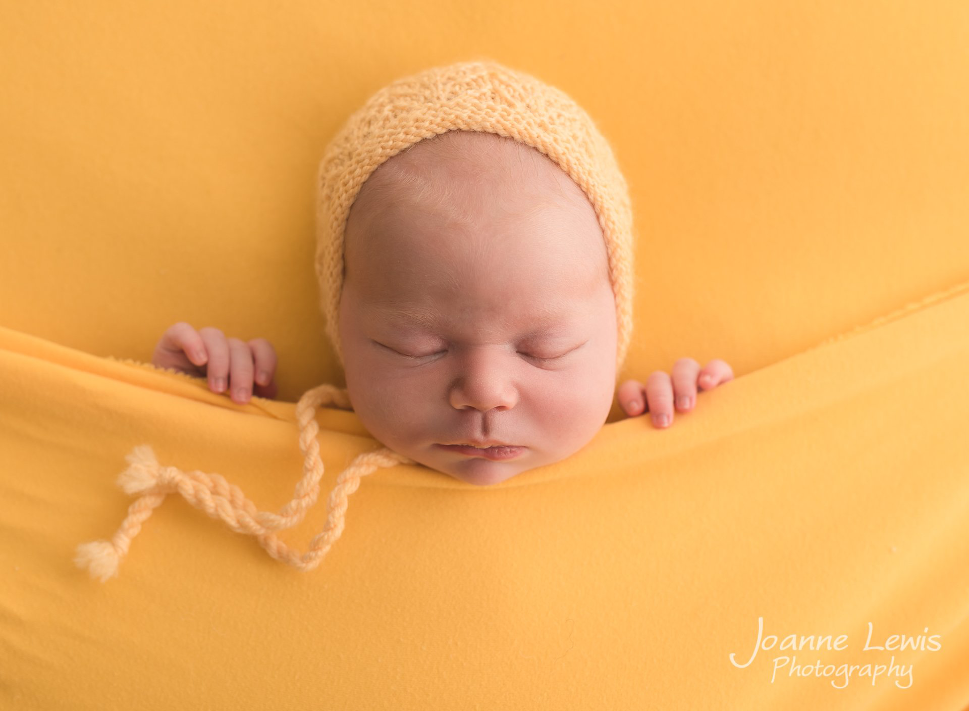 Newborn baby photoshoot. Asleep in a yellow bed style blanket