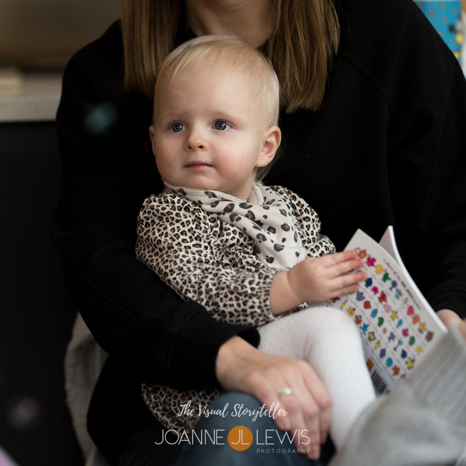 Baby sitting on mums lap reading birthday card