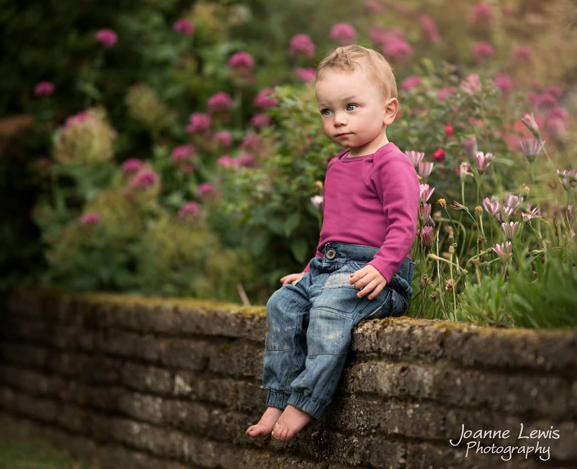 toddler sitting on a wall wearing pink tp and jeans