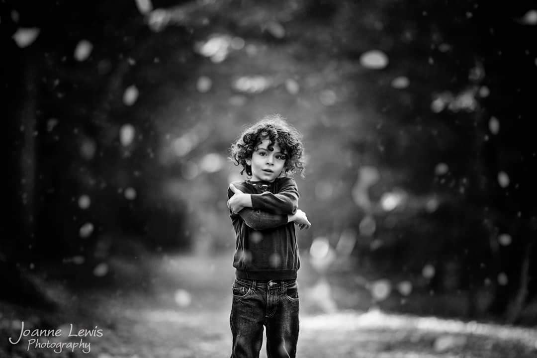 Black and White image of boy with curly hair shivering in the snow