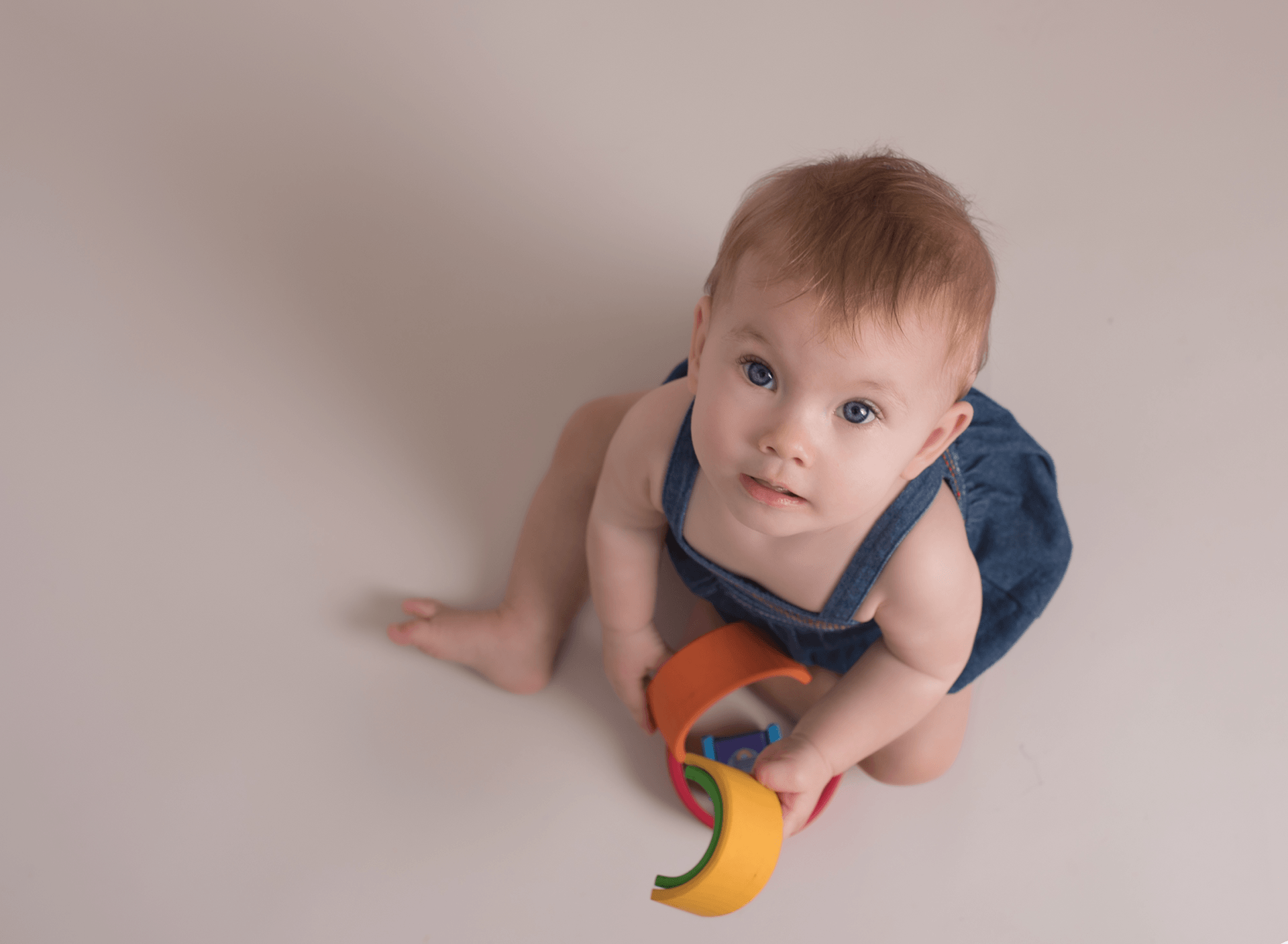 Little girl playing with Melissa and Doug bright wooden rainbow for sitter photo session