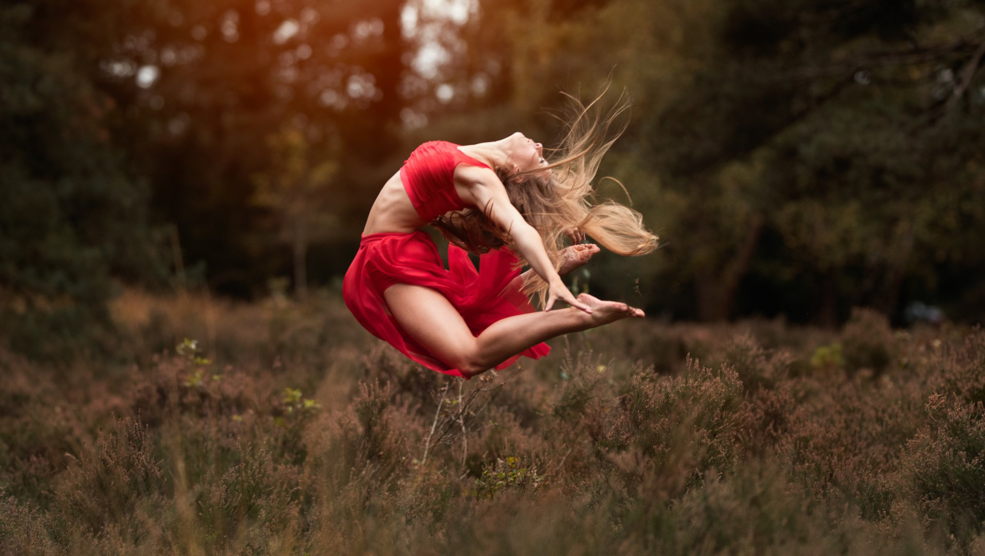 Ballet modern contemporary dance leap by dancer in heather field wearing red dress