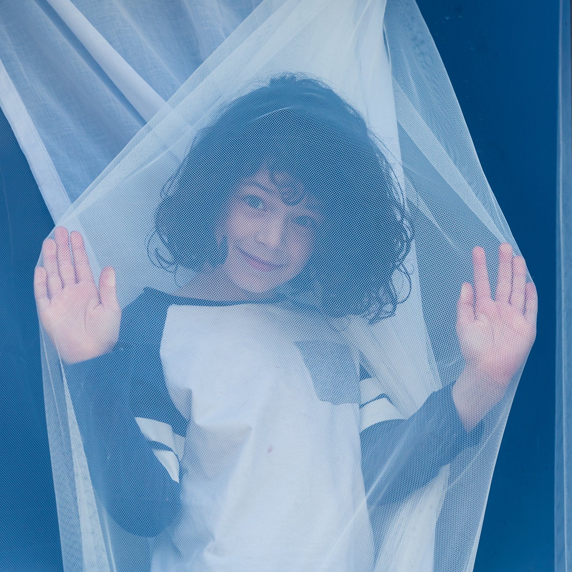 Young boy wrapped up in a net curtain