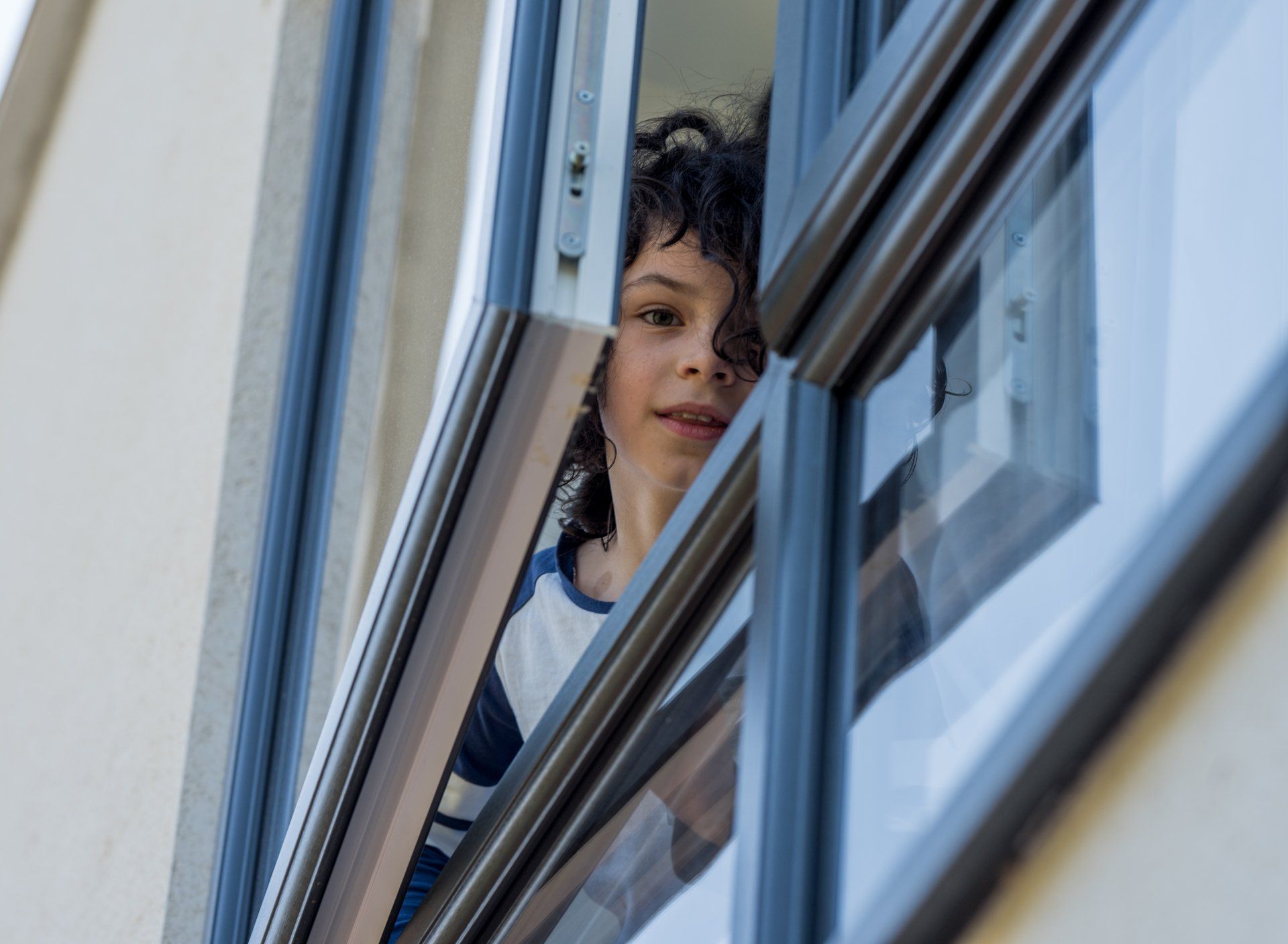 Young boy looking down out of 2nd floor window