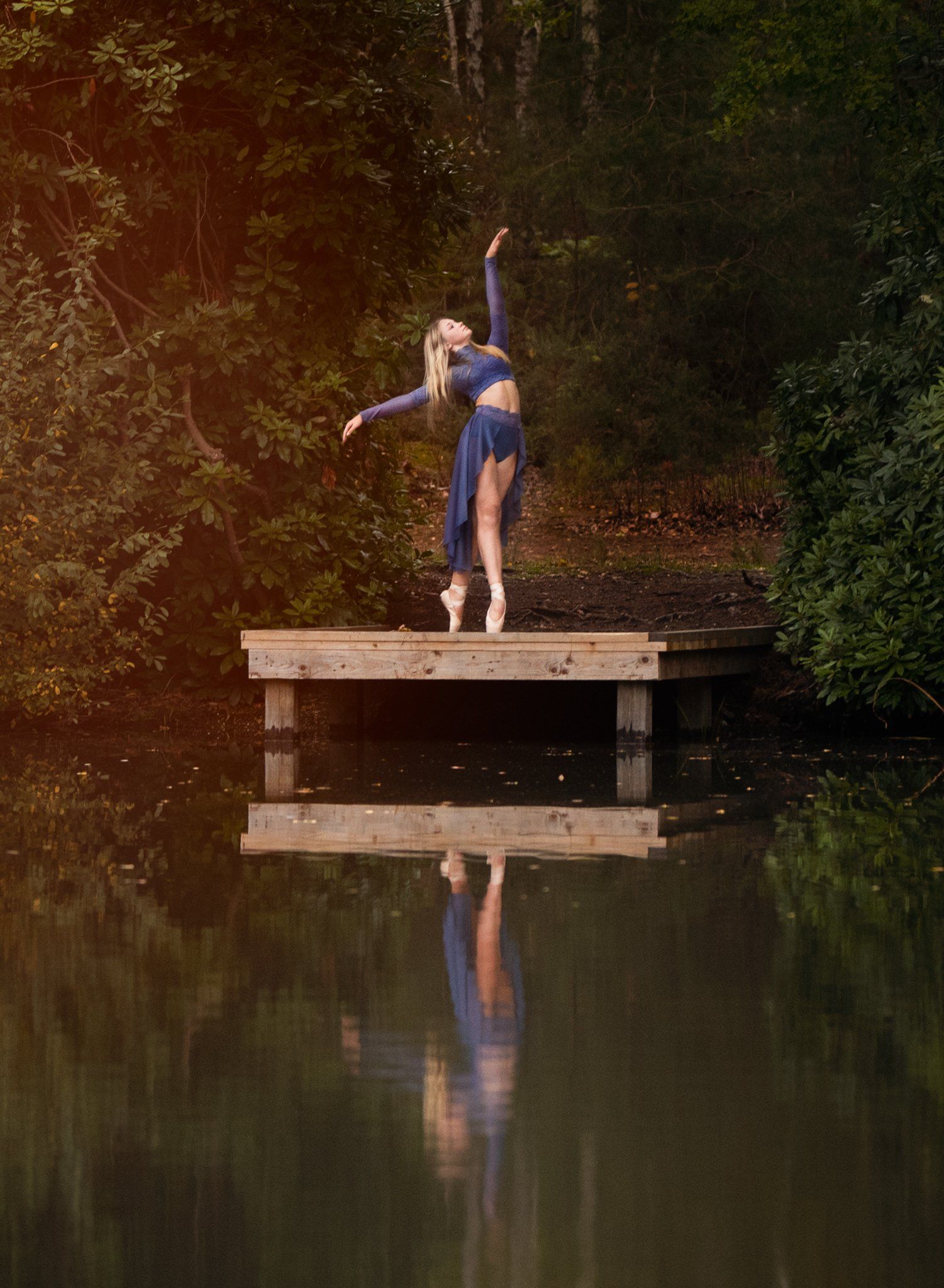 Ballet dancer at the edge of a lake during sunset