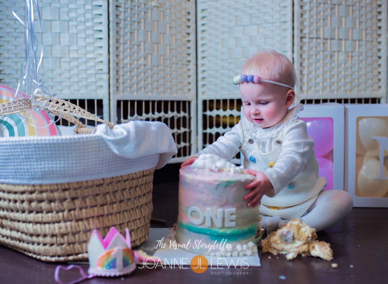 Tucking into rainbow cake at first birthday cake smash photography session in Harlow